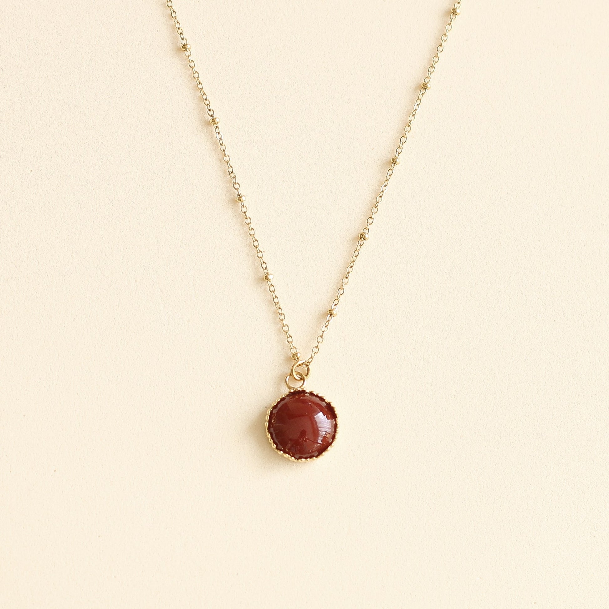collier avec un pendentif doré et une pierre de Cornaline rouge sur chaine dorée 