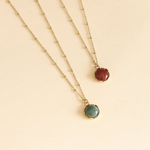 collier avec un pendentif doré et sa pierre de Cornaline sur une chaine à boules dorée 