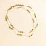 collier sautoir avec une chaine longue dorée et des perles vertes