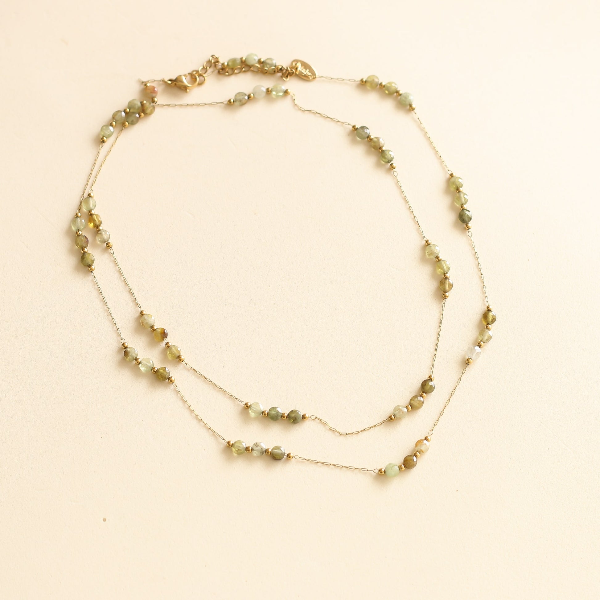 collier sautoir avec une chaine longue dorée et des perles vertes